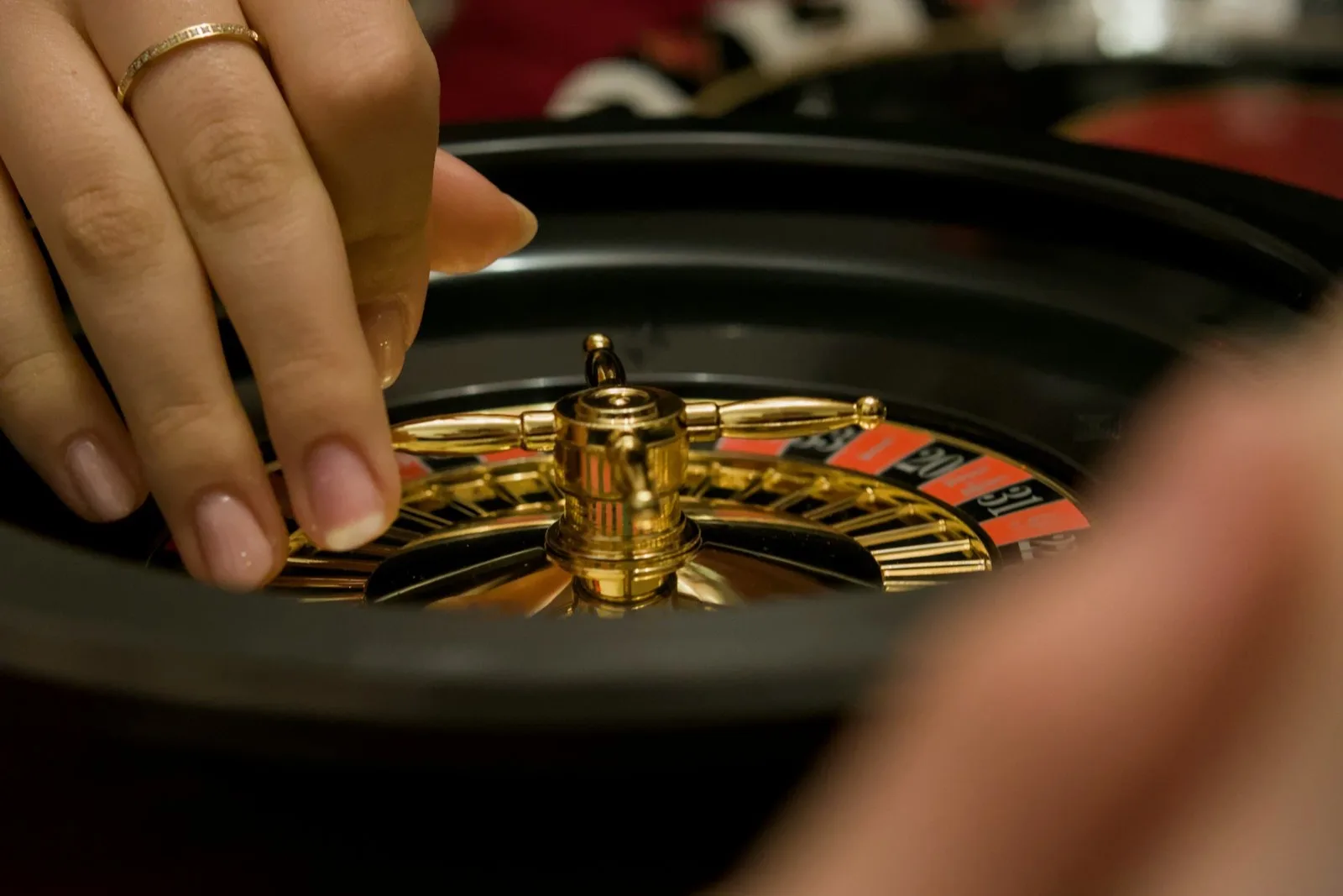 Close-up of a gold and black roulette wheel with a player about to release the ball