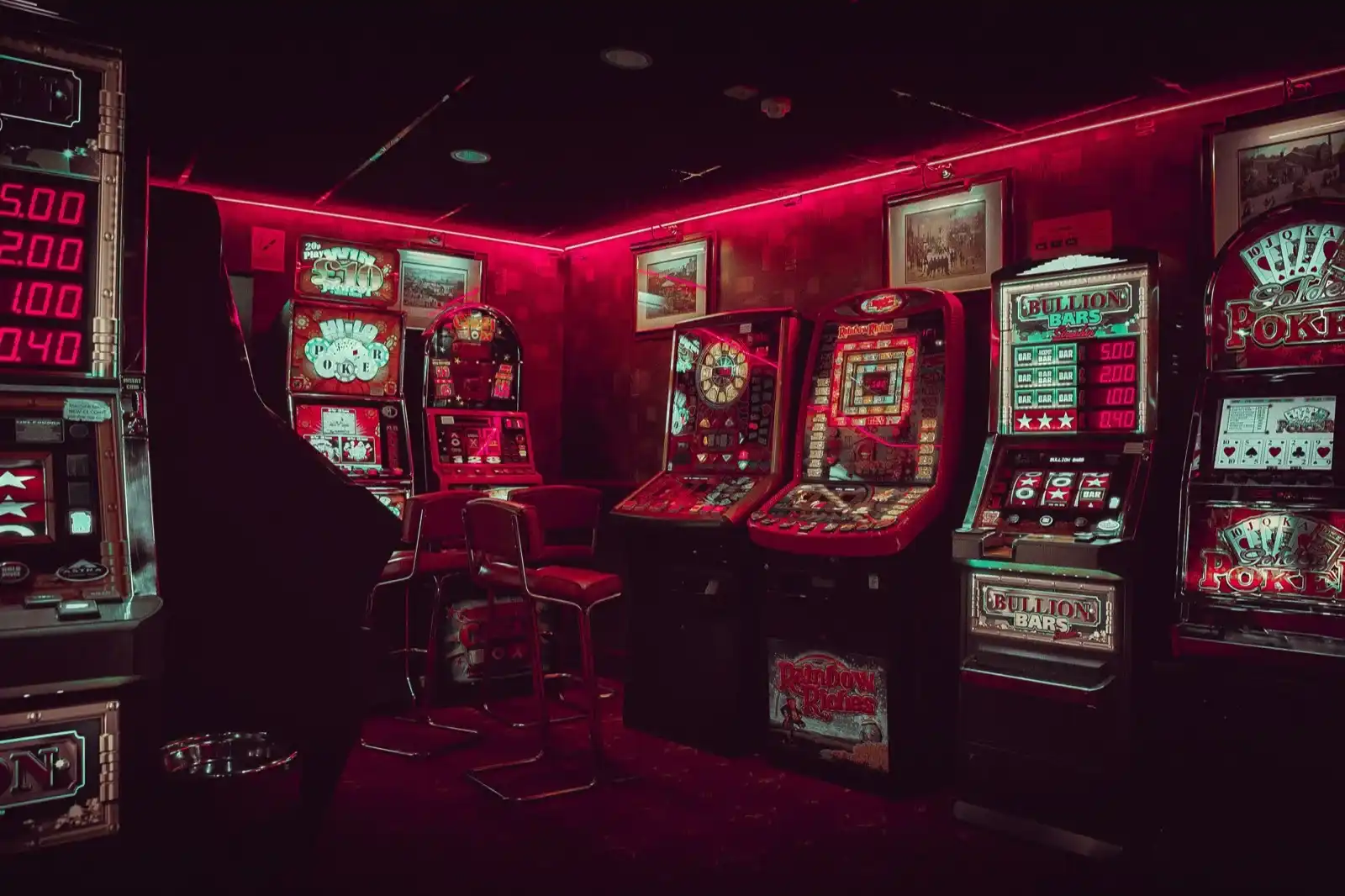 Row of illuminated slot machines in a dimly lit casino aisle